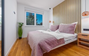 Relax in a serene bedroom with a large bed, potted plant, and a window offering a clear view.