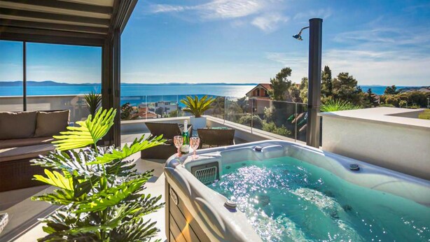 Una terraza en la azotea con jacuzzi, zona de estar y vistas al mar.