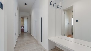 Un pasillo moderno con un banco, un espejo grande y una puerta que da a un dormitorio.