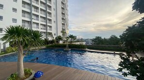 Relax by the pool surrounded by lush greenery and palm trees.