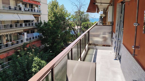 Un balcon donnant sur les bâtiments et les arbres des environs.
