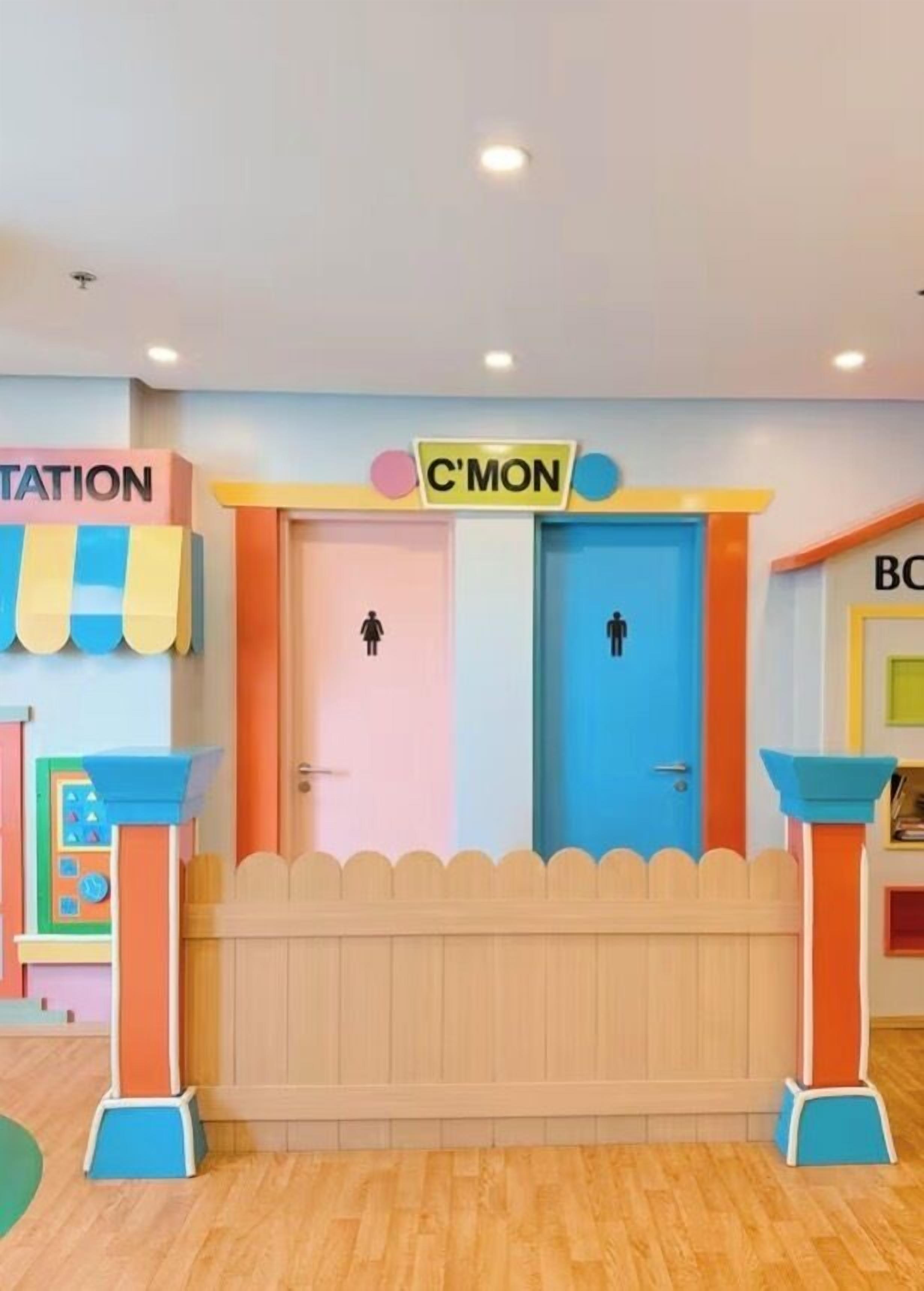 A children's play area with two doors labeled 'C'MON' and 'STATION', each with a gender symbol.