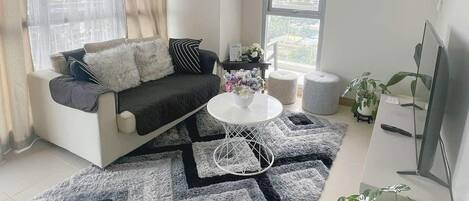 A modern living room with a sofa, a coffee table, and a large window.