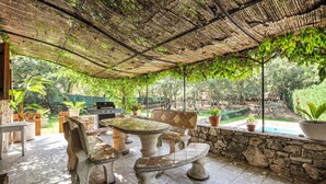 An outdoor patio with a table and chairs, a grill, and a stone wall. - Amazing home in Fayence (Fayence)