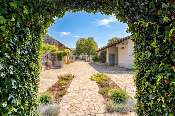 Un patio empedrado con un camino central, rodeado de edificios y vegetación.