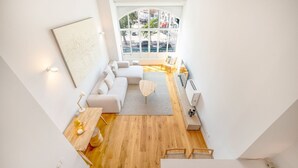 Een moderne woonkamer met een groot raam, een zithoek, een salontafel en een bijzettafeltje.
