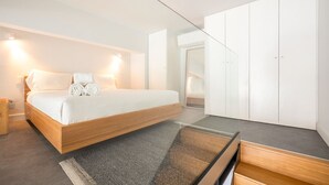 Een moderne slaapkamer met een groot bed, een garderobe en een klein bureau.