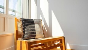 Een houten stoel met een geweven kussen in een kamer met een groot raam.