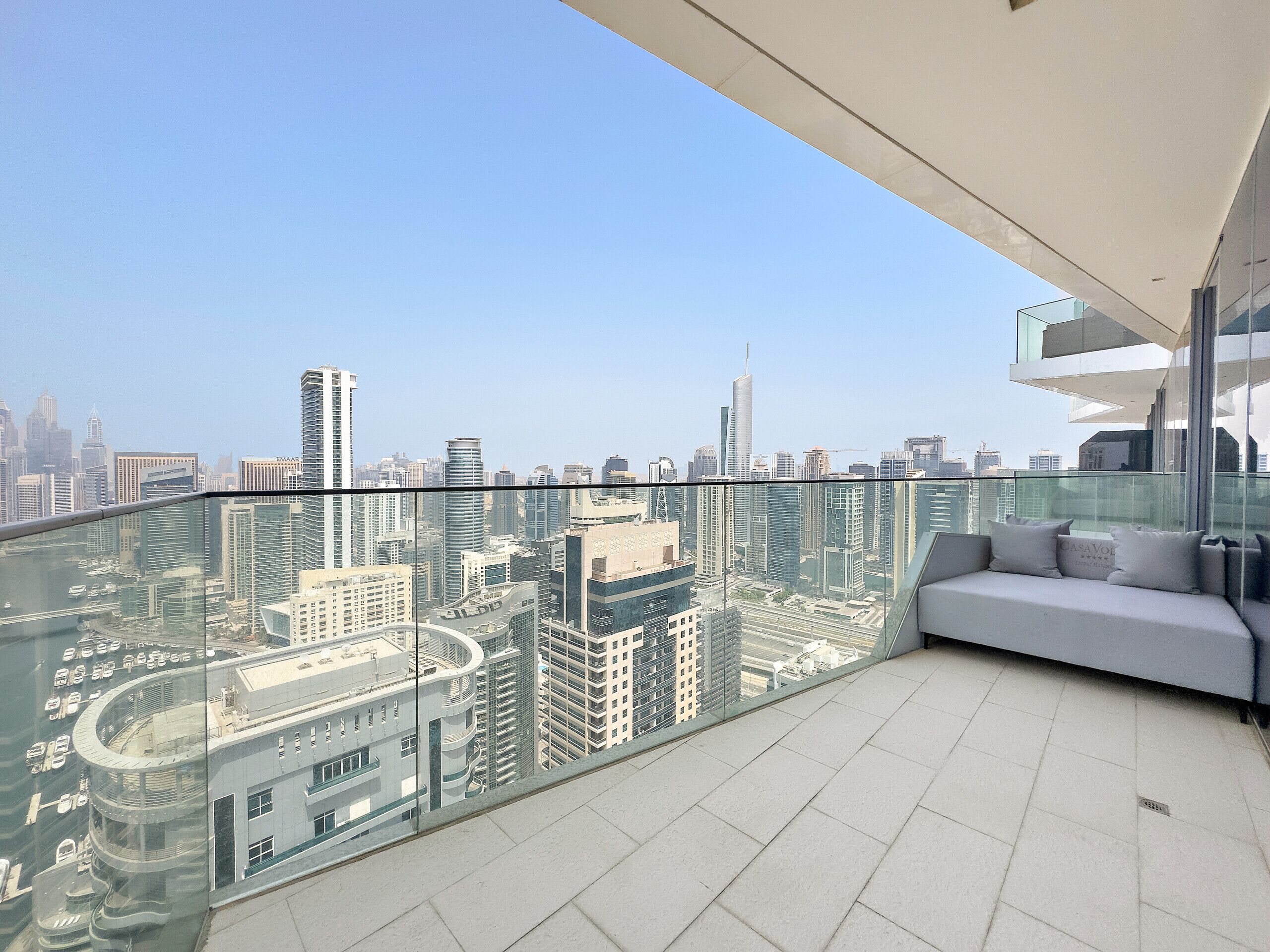 A modern balcony with a glass railing overlooking a cityscape.