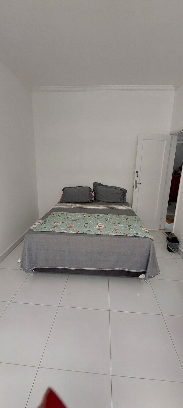 A bedroom with a bed, pillows, and a door.