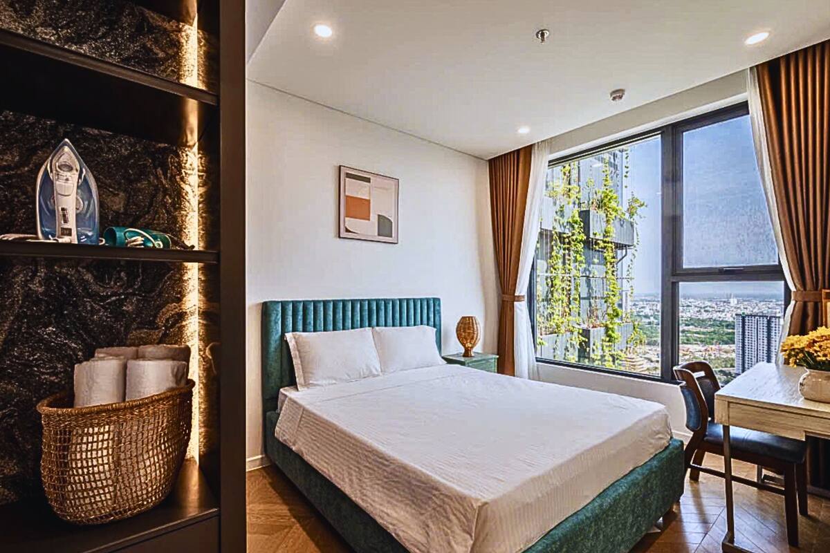 Ein modernes Hotelzimmer mit einem großen Bett, einem Schreibtisch und Blick auf die Stadt durch große Fenster.