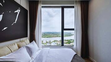 A hotel room with a large bed, a view of a river and cityscape, and a modern design.