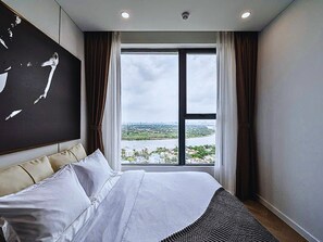 A hotel room with a large bed, a view of a river and cityscape, and a modern design. - The Lumiere Luxury Citypoint ANGIA (Ho Chi Minh City)