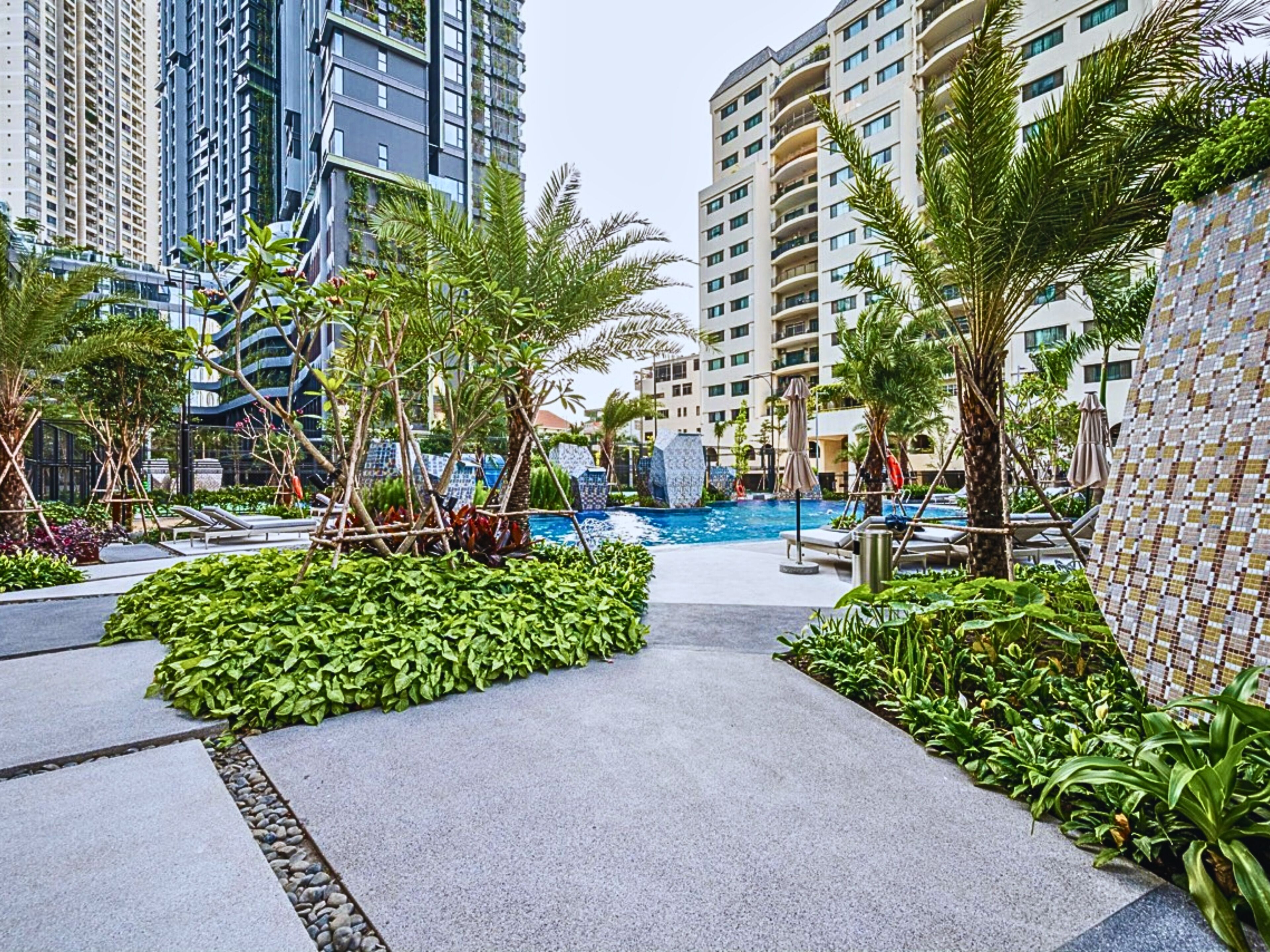Un hotel modern amb una piscina envoltada de vegetació exuberànt i palmeres.