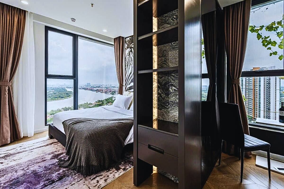 Ein modernes Schlafzimmer mit einem großen Bett, einem Einbauschrank, einem Schreibtisch und Blick auf eine Stadtlandschaft.
