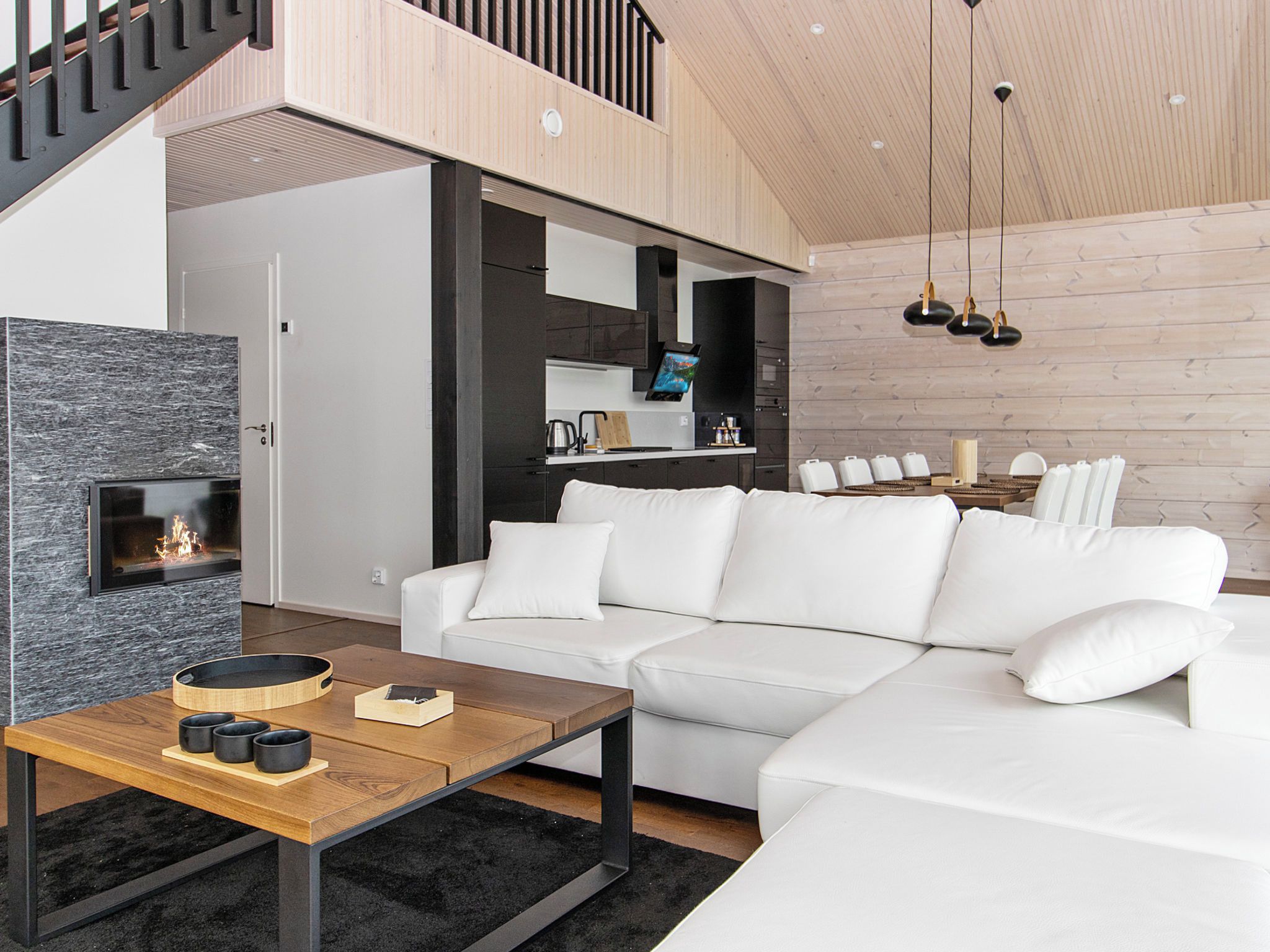 A modern living room with a white sofa, a wooden coffee table, and a fireplace.