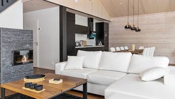 A modern living room with a white sofa, a wooden coffee table, and a fireplace.