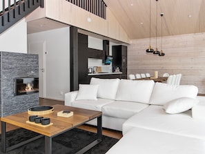 A modern living room with a white sofa, a wooden coffee table, and a fireplace. - Villa kirsikka by Interhome (Hämeenlinna)