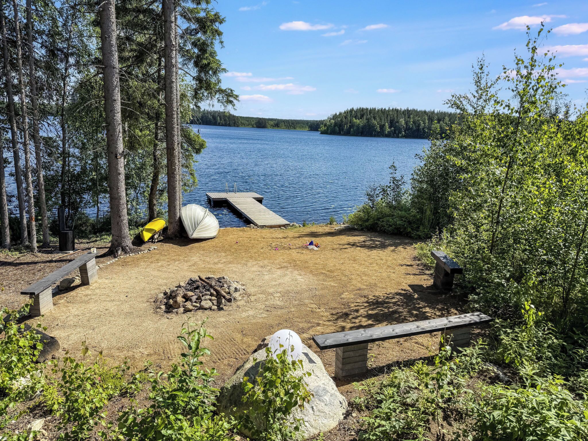 A lakeside campsite with a dock, a fire pit, and a bench.