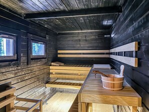 Una sala de sauna con bancos de madera y un balde de madera.