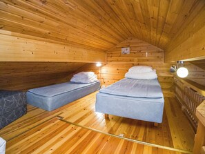 A cozy cabin with two single beds, wooden walls, and a sloped ceiling. - Operomukka 5 by Interhome (Kittilä)