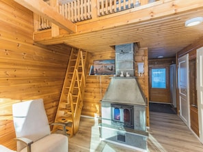 A wooden cabin interior with a fireplace, a ladder, and a sofa. - Operomukka 5 by Interhome (Kittilä)