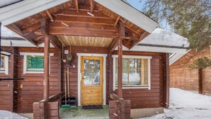 A wooden cabin with a covered porch, a front door, and a window. - Operomukka 5 by Interhome (Kittilä)