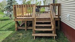 Una terraza de madera con una escalera que sube hacia una casa.