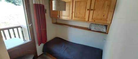 Ein Zimmer mit einem Holzkasten, einer Bank und einem Fenster mit Vorhängen.