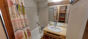 Une salle de bain avec une baignoire, un lavabo et un miroir.