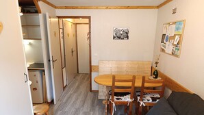 A compact living space with a kitchenette, a dining area with a wooden table and chairs, and a sofa with a decorative pillow. - Paradiski closed to the slopes vallandry (LANDRY)