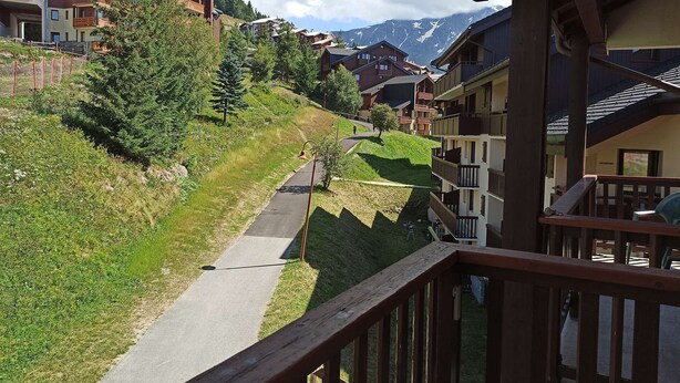 A mountain resort with a paved path, wooden buildings, and a view of snow-capped mountains. - Paradiski closed to the slopes vallandry (LANDRY)