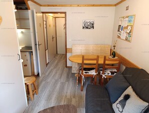 Un intérieur chaleureux avec un coin repas, un canapé et une cuisine visible au fond.