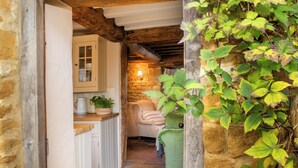 A cozy kitchen with stone walls, a wooden ceiling, and a green plant on the right. - Charming 2BD in the Heart of Kingham (Chipping Norton)