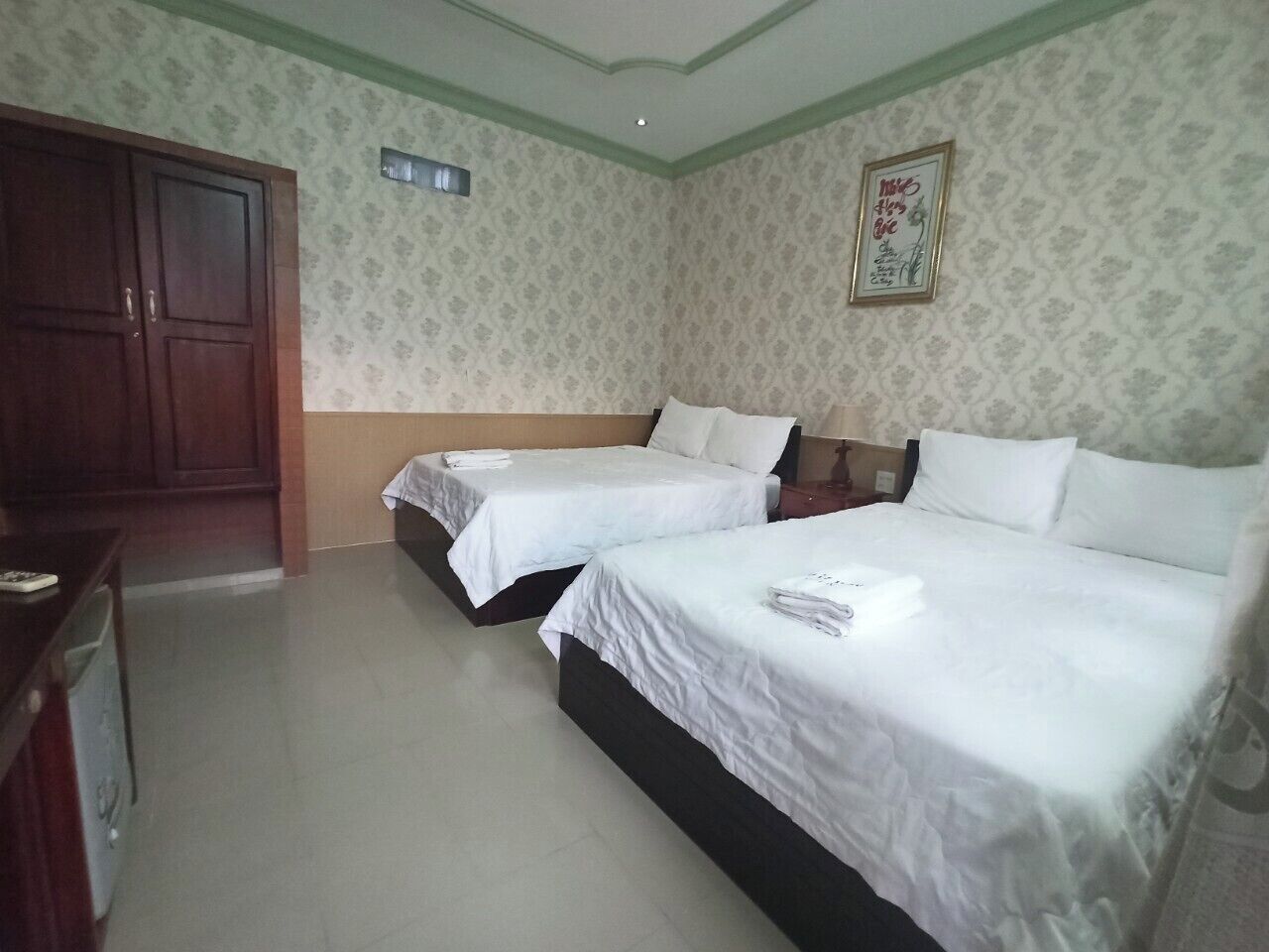 Ein Hotelzimmer mit zwei Betten, einem Kleiderschrank und einem kleinen Schreibtisch.