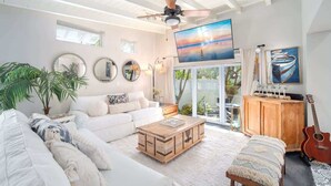 A spacious living room with a white sofa, a wooden coffee table, and a ceiling fan.