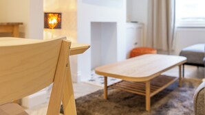 A modern living room with a wooden table and chairs, a small rug, and a sofa. - Bright & Airy 2BD - 10min walk to Centre (Cheltenham)
