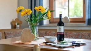 A dining table with a bottle of wine, a bowl, a heart-shaped object, and a vase with yellow flowers. - Group home on a farm only 80 m from the ski bus (Reith im Alpbachtal)