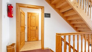 A wooden staircase with a handrail, a fire extinguisher, and a wooden door leading to another room. - Group home on a farm only 80 m from the ski bus (Reith im Alpbachtal)