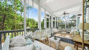 A covered outdoor seating area with white furniture, including a sofa and chairs, and a table. - 3BR WaterColor Escape w/ Beach Club Access, Golf Cart, 4 Bikes & Spacious Deck for Outdoor Dining. (Santa Rosa Beach)