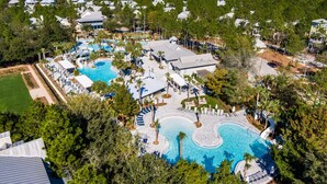 An aerial view of a resort with multiple swimming pools, a large building, and surrounding greenery. - 3BR WaterColor Escape w/ Beach Club Access, Golf Cart, 4 Bikes & Spacious Deck for Outdoor Dining. (Santa Rosa Beach)