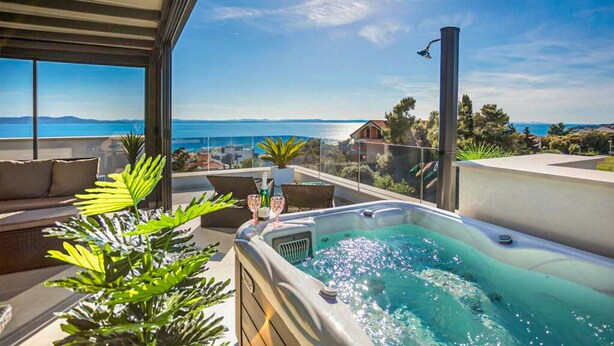 En tagterrasse med jacuzzi, siddepladser og havudsigt.