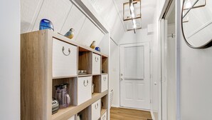 Um corredor com estantes de madeira, uma porta branca e um luminário.