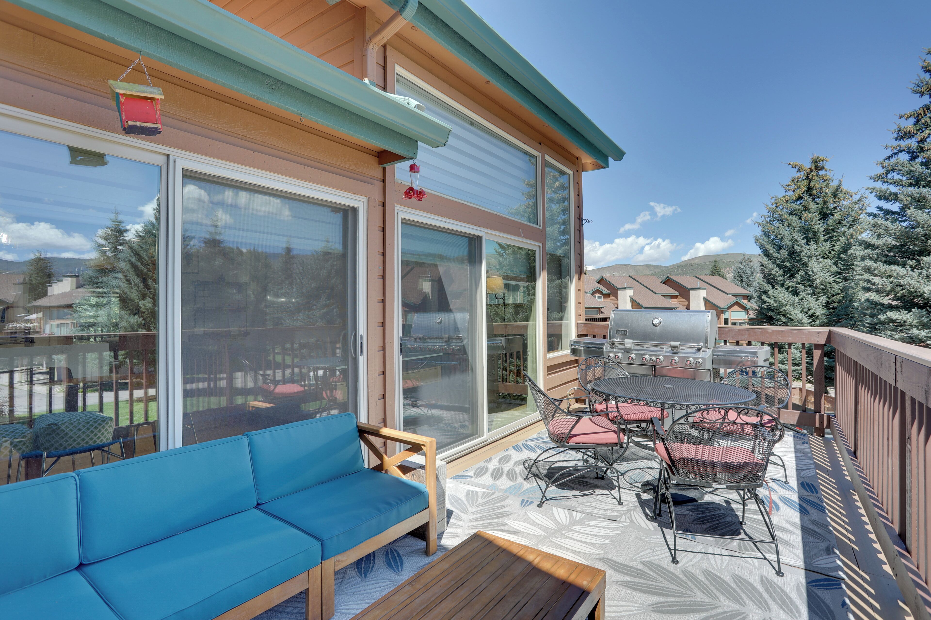 A covered outdoor patio with a blue sofa, a table, and chairs.