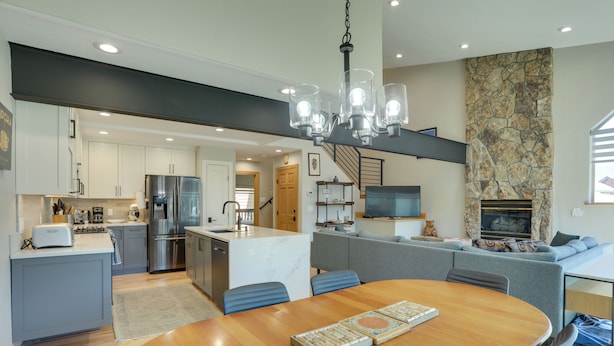 Una cocina moderna con una isla central, electrodomésticos de acero inoxidable y un comedor con mesa y sillas de madera.