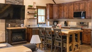Una cocina acogedora con armarios de madera, una pared de acento de piedra, una chimenea y un comedor con mesa y sillas.