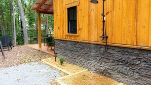Una cabaña de madera con base de piedra, una ventana y un cabezal de ducha.