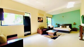 Una habitación de hotel con cama, sofá, mesa de centro y televisor.