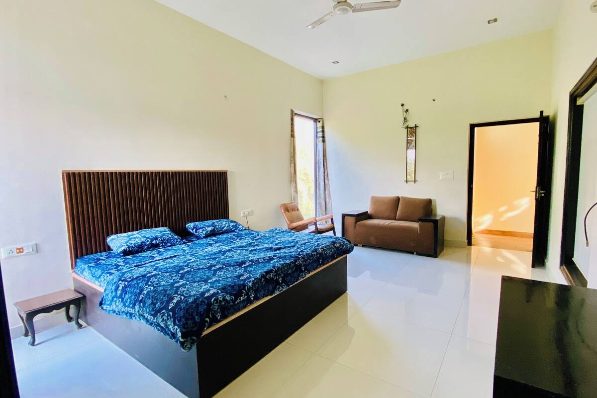 A bedroom with a large bed, a sofa, a chair, and a desk.