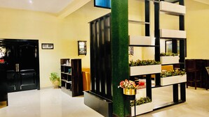 Un vestíbulo moderno con una estantería blanco y negro, un detalle vertical verde y una planta con flores.
